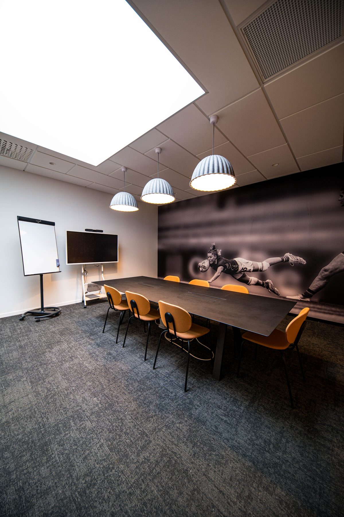 Salle de formation du campus : grande table, écran, paperboard et fresque murale